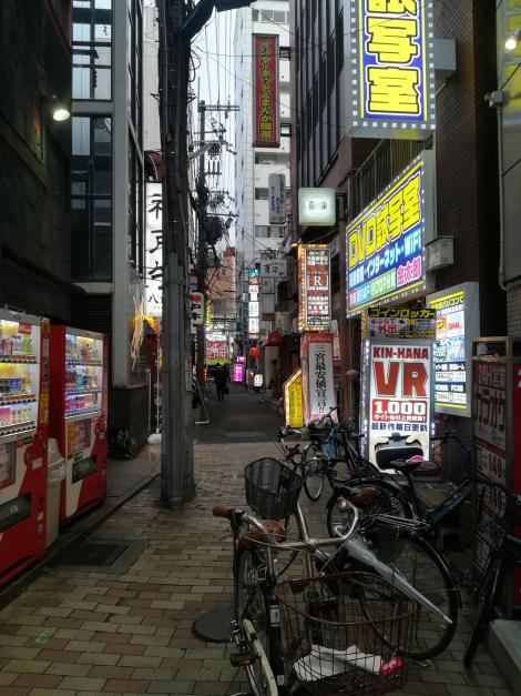 Zdjęcie nr 13 (13)
                                	                             Zdjęcie Tomasza Jakutowicza z pobytu w Japonii. Zdjęcie przedstawia miejską uliczkę z szyldami reklamowymi.
                            